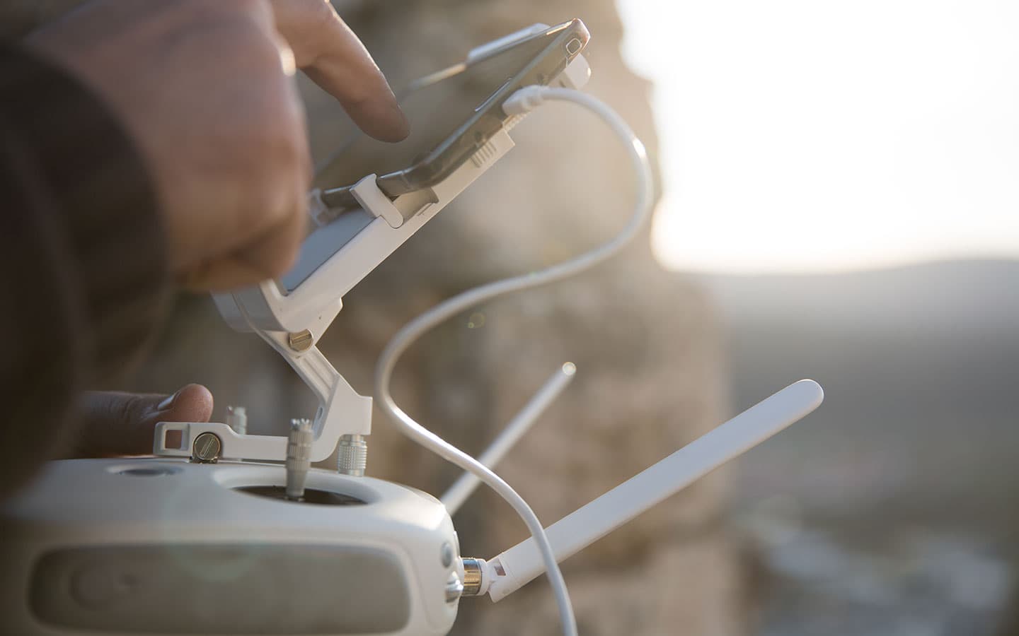 Mãos segurando controle remoto de drone profissional com iluminação dourada